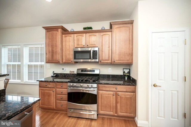 kitchen featuring dark stone counters, stainless steel appliances, and light wood-style floors