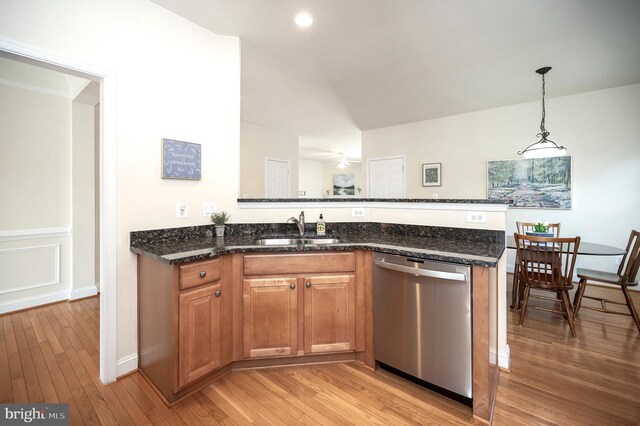 kitchen featuring a sink, a peninsula, light wood finished floors, and stainless steel dishwasher