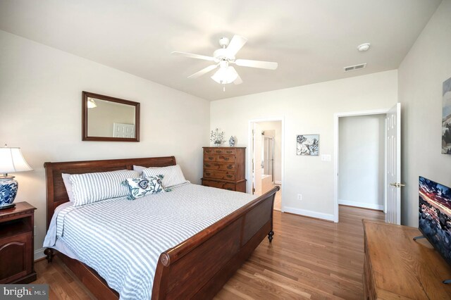 bedroom with baseboards, visible vents, a ceiling fan, and wood finished floors
