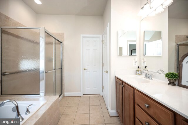 bathroom featuring baseboards, vanity, a stall shower, a garden tub, and tile patterned flooring