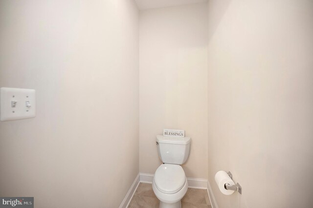 bathroom featuring baseboards, toilet, and tile patterned flooring