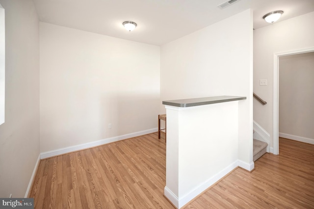 corridor featuring baseboards, visible vents, wood finished floors, and stairway