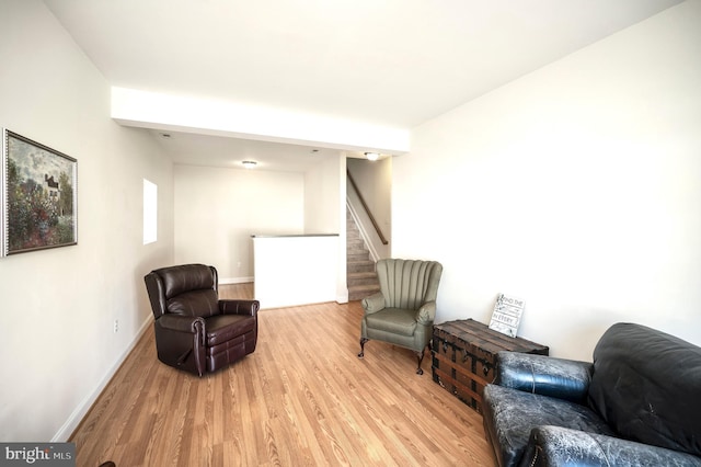 living area with baseboards, stairway, and wood finished floors