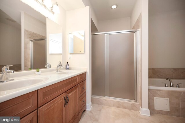 bathroom with double vanity, a sink, tiled tub, and a shower stall