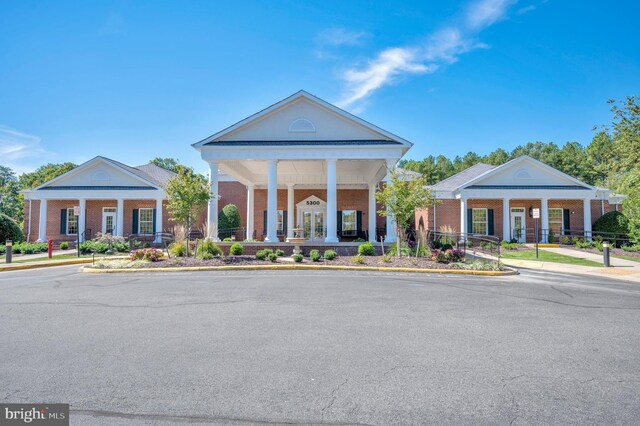 neoclassical / greek revival house with french doors, brick siding, and covered porch