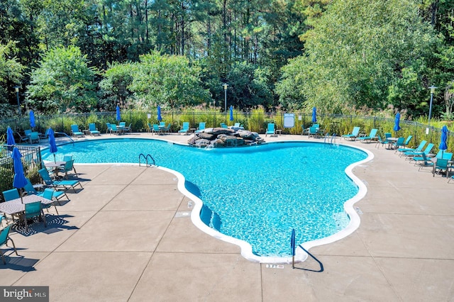 pool with a patio area and fence