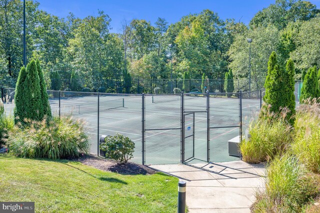view of sport court with a lawn and fence