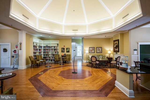 living area with built in features, baseboards, visible vents, a towering ceiling, and ornamental molding