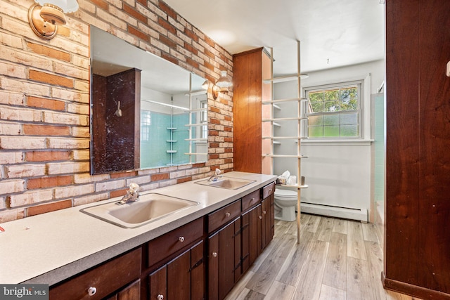 bathroom featuring wood finished floors, toilet, baseboard heating, and a sink