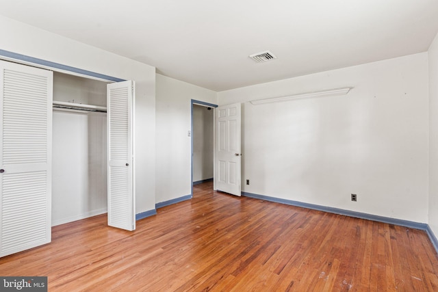 unfurnished bedroom featuring a closet, visible vents, light wood finished floors, and baseboards