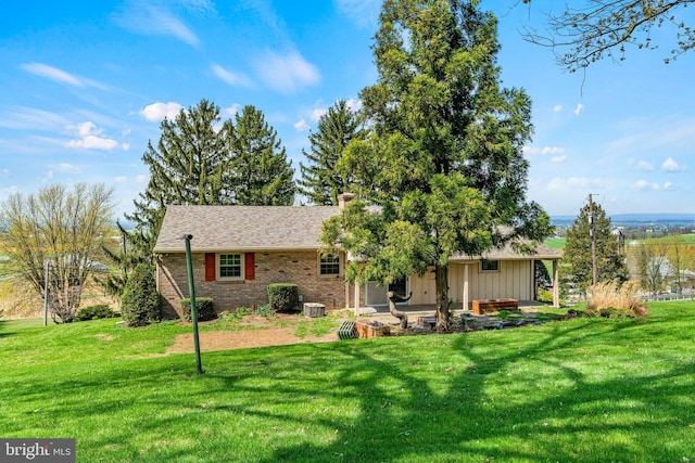 back of house with brick siding, a yard, central AC, and a chimney