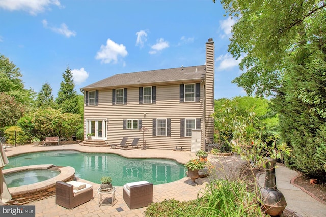 view of pool with a patio area, an in ground hot tub, french doors, and a fenced in pool