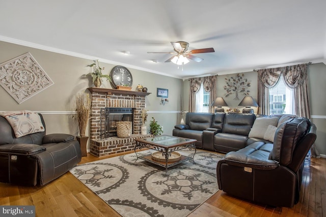 living room featuring ornamental molding, a fireplace, ceiling fan, and wood finished floors