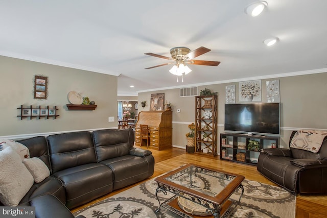 living area featuring wood finished floors, a ceiling fan, and ornamental molding