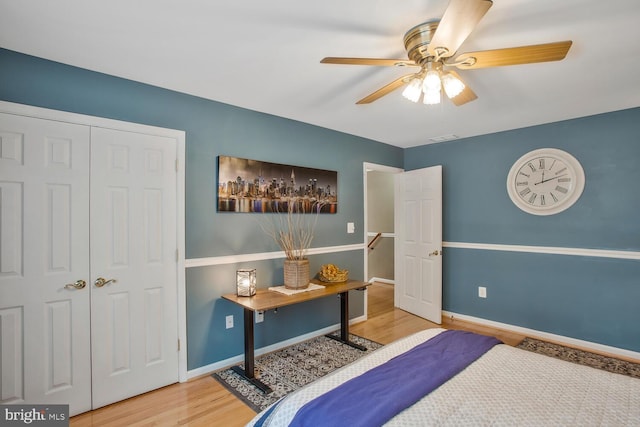 bedroom with wood finished floors, a closet, visible vents, baseboards, and ceiling fan