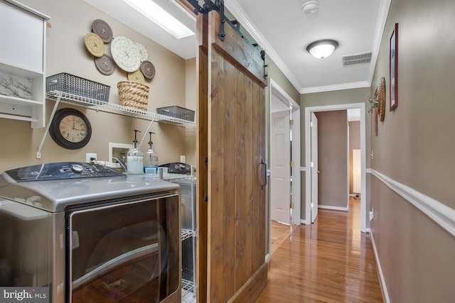 laundry area with washing machine and clothes dryer, laundry area, visible vents, a barn door, and ornamental molding