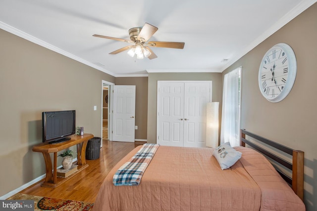 bedroom featuring crown molding, a closet, baseboards, and wood finished floors