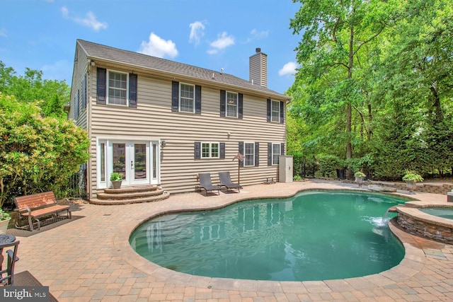 view of pool with a pool with connected hot tub, a patio area, and french doors