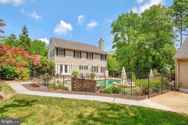 back of house with a chimney, a yard, a fenced in pool, fence, and a patio area