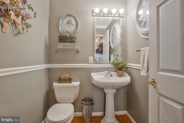 half bathroom featuring toilet, wood finished floors, and ornamental molding