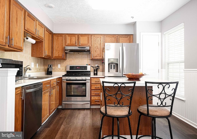 518 Macintosh Cir, Joppa, MD 21085 - kitchen with under cabinet range hood, appliances with stainless steel finishes, light countertops, dark wood-style flooring, and a sink