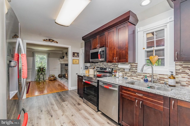 2220 Timothy Dr, Westminster, MD 21157 - kitchen with a warm lit fireplace, light stone countertops, appliances with stainless steel finishes, a sink, and light wood-style floors
