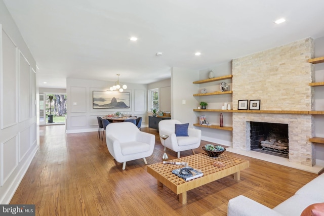 living room with a decorative wall, recessed lighting, wood finished floors, and a chandelier