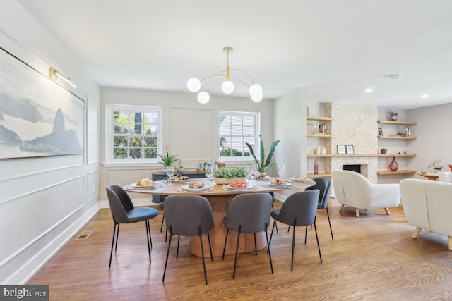 dining room with visible vents, a fireplace, recessed lighting, a chandelier, and light wood finished floors