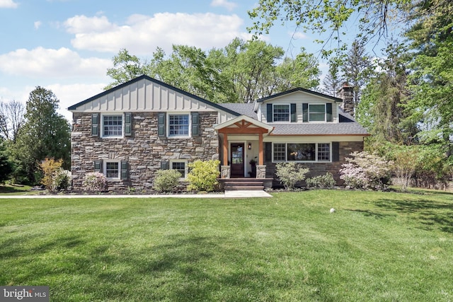view of front of house with board and batten siding, a chimney, roof with shingles, a front yard, and stone siding