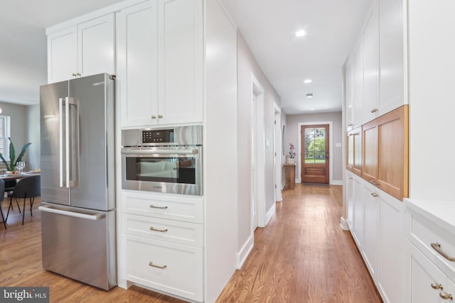 kitchen with light wood finished floors, white cabinetry, and stainless steel appliances