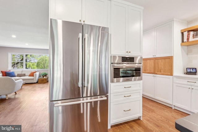 kitchen with open shelves, open floor plan, white cabinets, light wood-style flooring, and stainless steel appliances