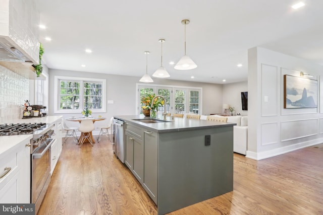 kitchen with gray cabinetry, appliances with stainless steel finishes, a sink, and light wood-style flooring