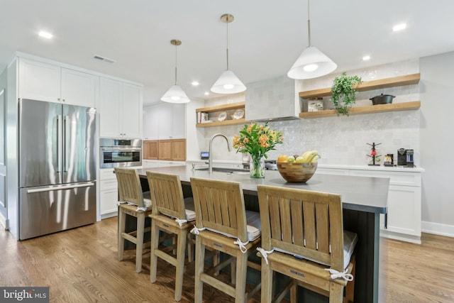 kitchen featuring open shelves, appliances with stainless steel finishes, a sink, decorative backsplash, and visible vents