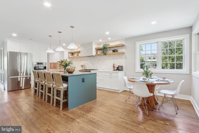 kitchen with open shelves, decorative backsplash, a center island with sink, white cabinetry, and stainless steel appliances