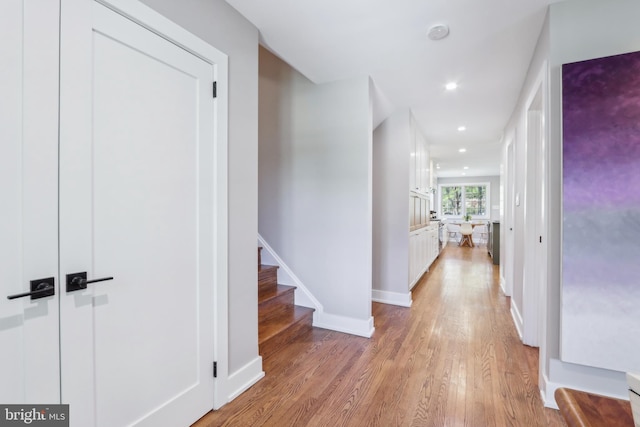 corridor with recessed lighting, baseboards, stairway, and light wood-type flooring