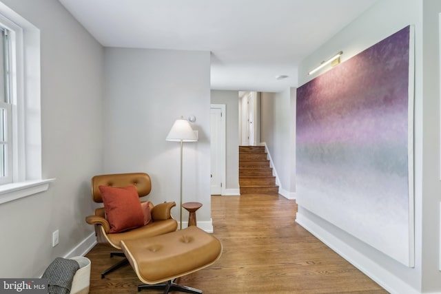living area with stairway, baseboards, and wood finished floors
