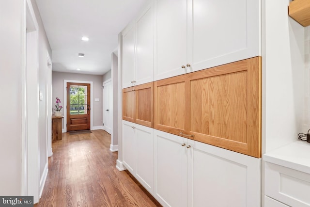 corridor featuring baseboards, recessed lighting, and light wood finished floors