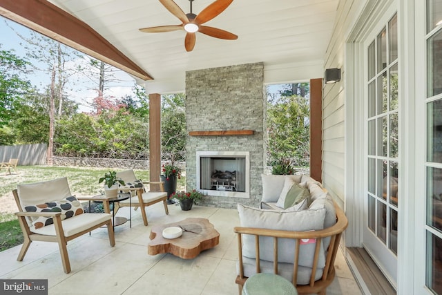 sunroom / solarium featuring an outdoor stone fireplace and ceiling fan