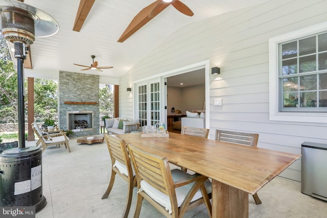 view of patio / terrace with an outdoor stone fireplace, a ceiling fan, and outdoor dining space