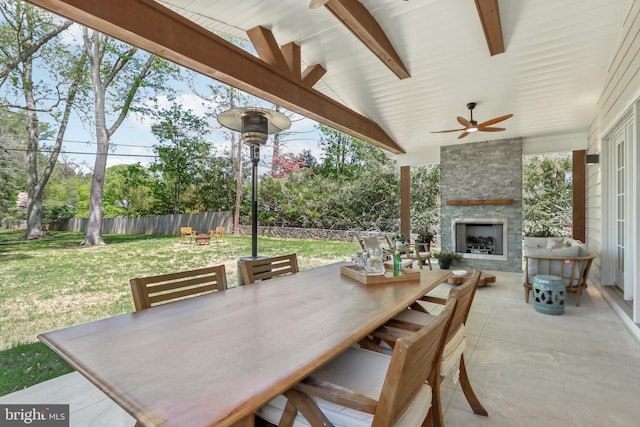 view of patio with a fenced backyard, a ceiling fan, outdoor dining space, and an outdoor stone fireplace