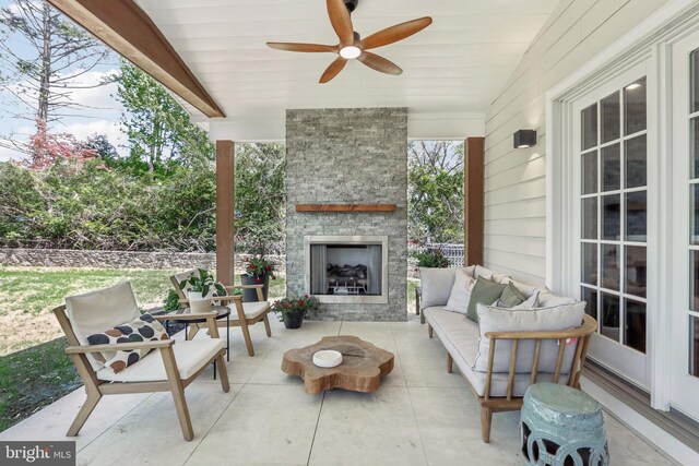view of patio / terrace with ceiling fan and an outdoor living space with a fireplace