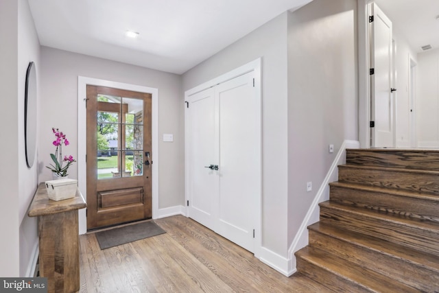 foyer with baseboards, stairs, wood finished floors, and visible vents