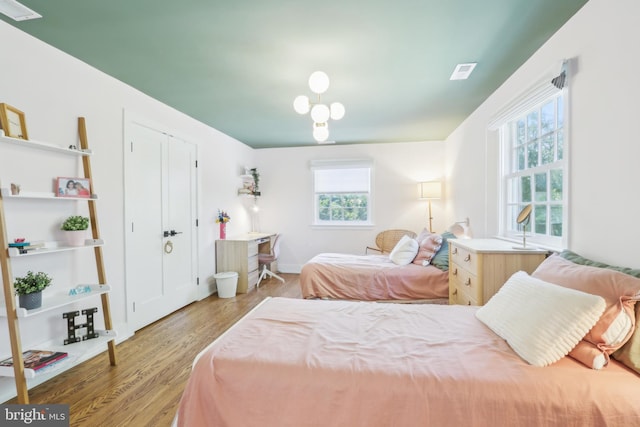 bedroom featuring visible vents, multiple windows, and wood finished floors