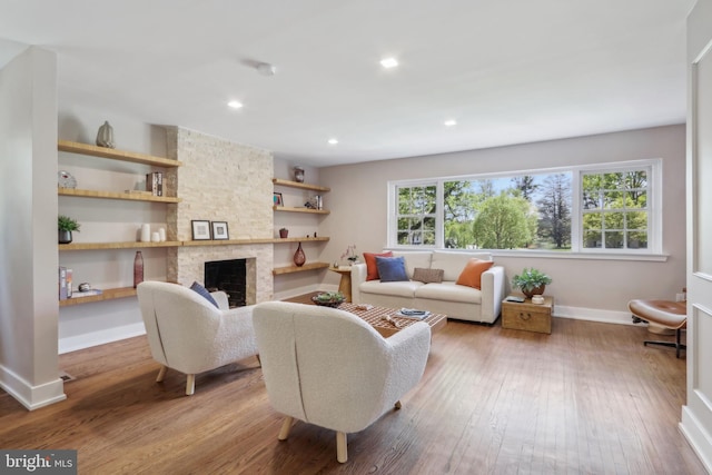 living room with recessed lighting, baseboards, a stone fireplace, and hardwood / wood-style flooring