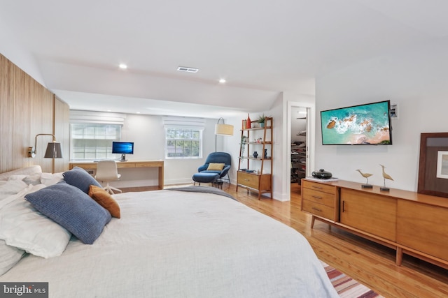 bedroom with recessed lighting, a walk in closet, light wood finished floors, and visible vents