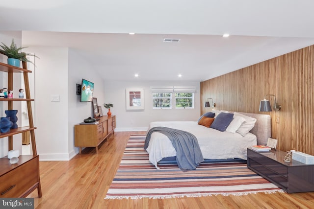 bedroom featuring visible vents, baseboards, wooden walls, recessed lighting, and light wood-type flooring
