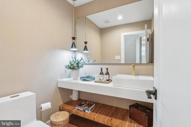bathroom with toilet, visible vents, and a sink
