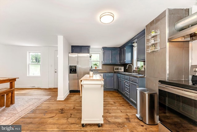 5431 Hines Rd, Frederick, MD 21704 - kitchen with a kitchen island, light wood-style floors, wall chimney range hood, a sink, and appliances with stainless steel finishes