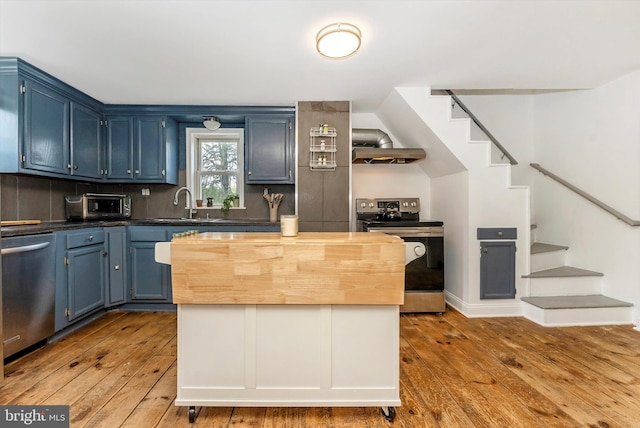 5431 Hines Rd, Frederick, MD 21704 - kitchen with a sink, wall chimney exhaust hood, hardwood / wood-style flooring, blue cabinets, and appliances with stainless steel finishes