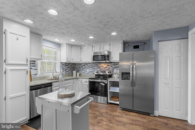 kitchen featuring a sink, decorative backsplash, white cabinetry, light countertops, and appliances with stainless steel finishes